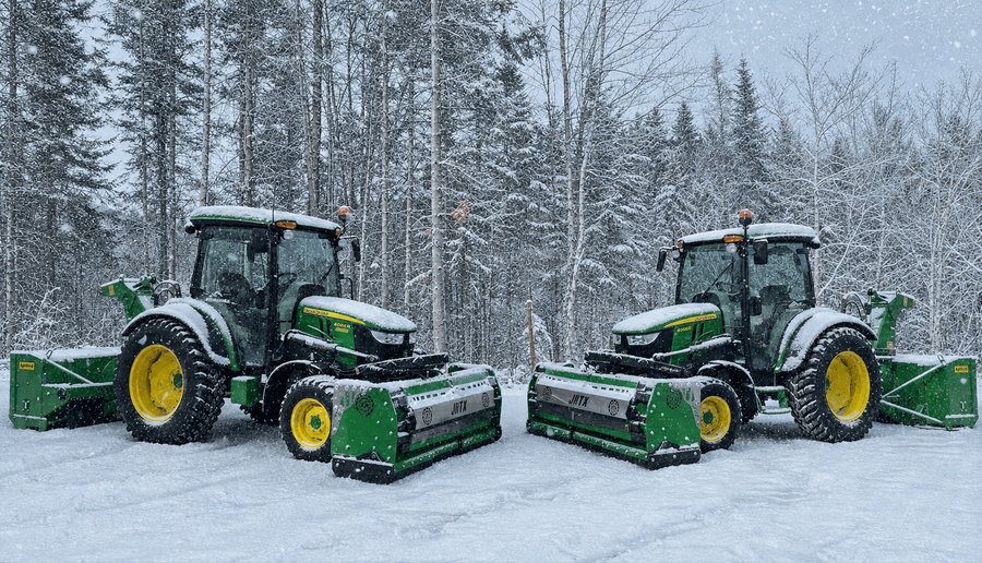 Deux tracteurs John Deere équipés de souffleuses à neige JRTX, couverts de neige, prêts à intervenir à Sainte-Brigitte-de-Laval